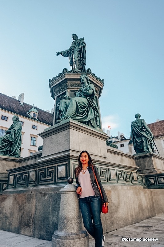 在市中心，女孩在维也纳的一座雕像前摆姿势