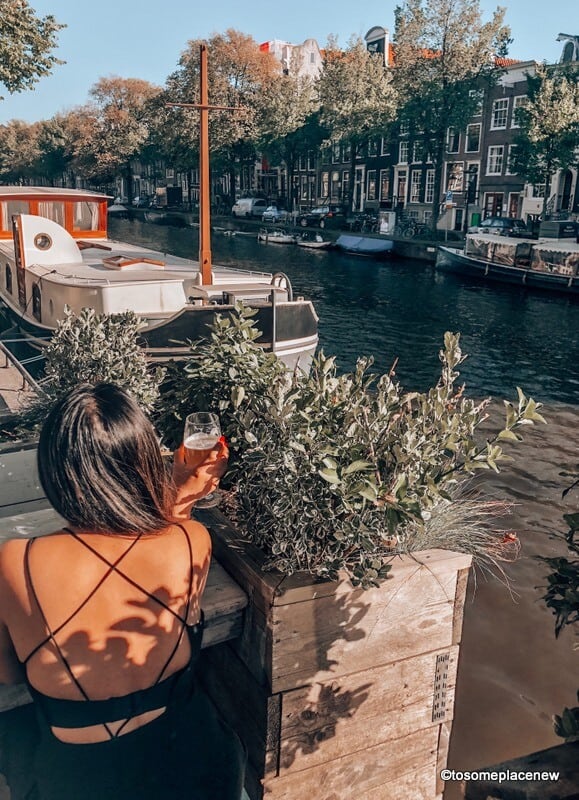 阿姆斯特丹是欧洲最美丽的城市之一，一个女孩在运河边喝啤酒