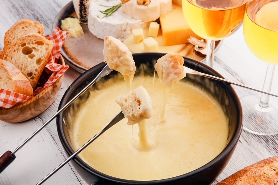 美味的瑞士奶酪火锅晚餐在一个冬天的晚上，在一个热锅奶酪火锅旁边有一个板上的什锦奶酪