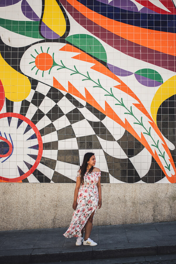 一个女孩站在波尔图牛排Shake餐厅外，墙上挂着彩色壁画